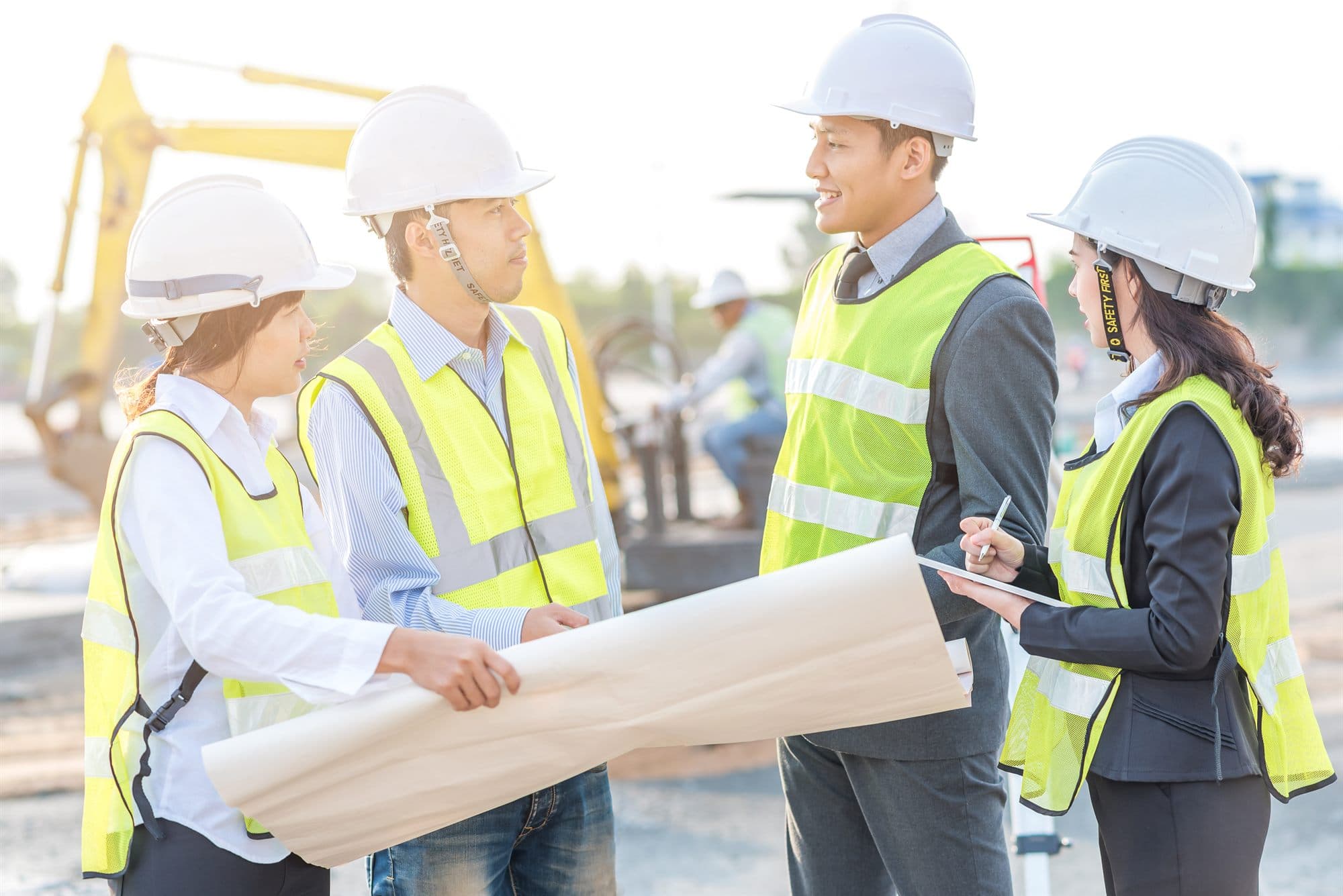 A construction crew in hard hats and safety vests reviewing project plans on site