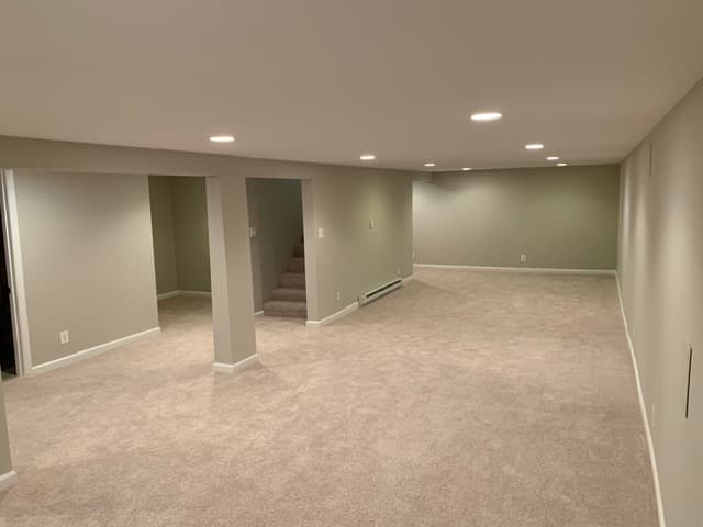 A finished basement with recessed lighting and new carpet