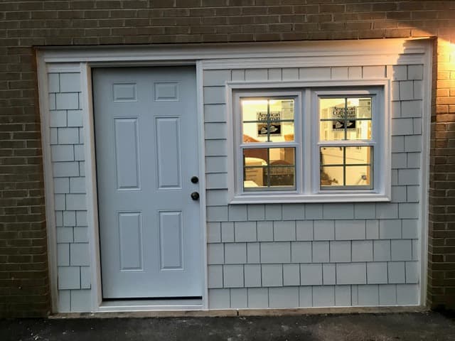 A garage converted into finished living space with a new door, window, and siding