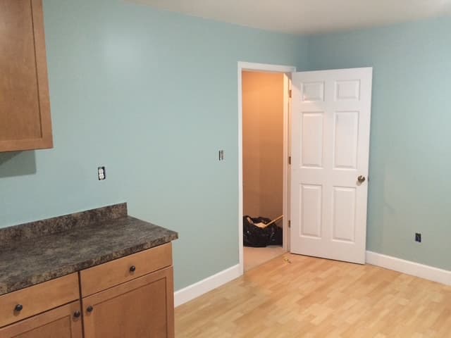 A finished basement room with new cabinets, countertop, paint, and flooring