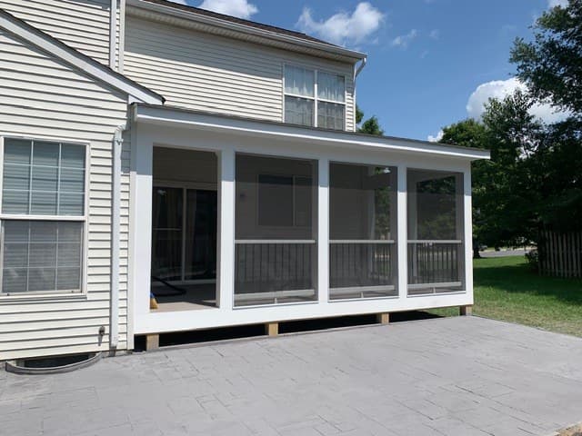 A newly built screened-in porch addition opening onto a stamped-concrete patio