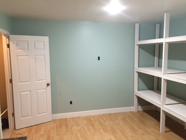 The same corner finished — painted walls, trim, laminate flooring and built-in shelving
