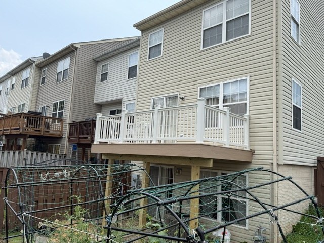 The same townhouse with the deck rebuilt, now with new boards and white railing
