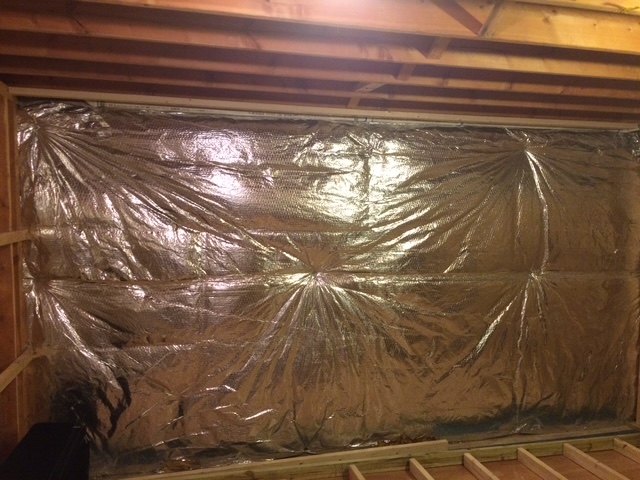 An insulated basement wall under exposed floor joists, before any finishing work