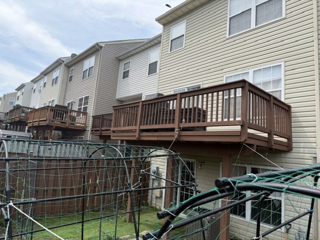 The back of a townhouse with its original wood deck, stained brown and weathered